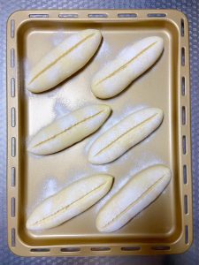 Dust the proofed buns with flour and cut a single slash 1-1.5 cm deep down the length of each one.