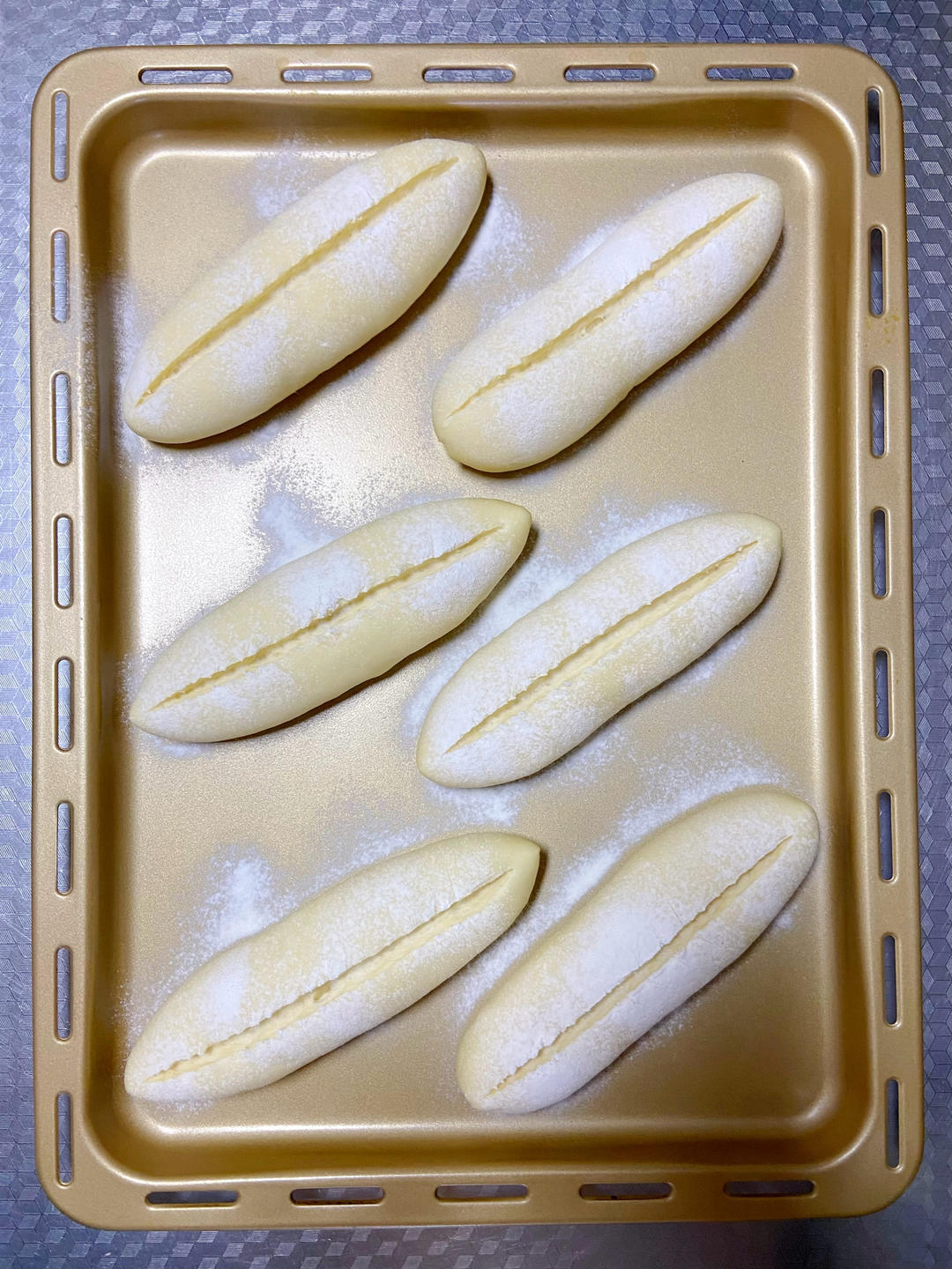 Dust the proofed buns with flour and cut a single slash 1-1.5 cm deep down the length of each one.