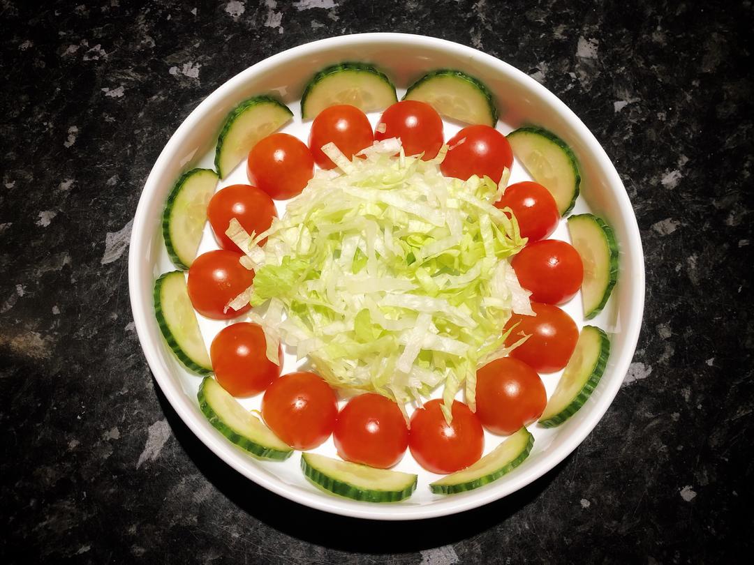 Arrange the lettuce, cucumber, and tomato in the serving dish