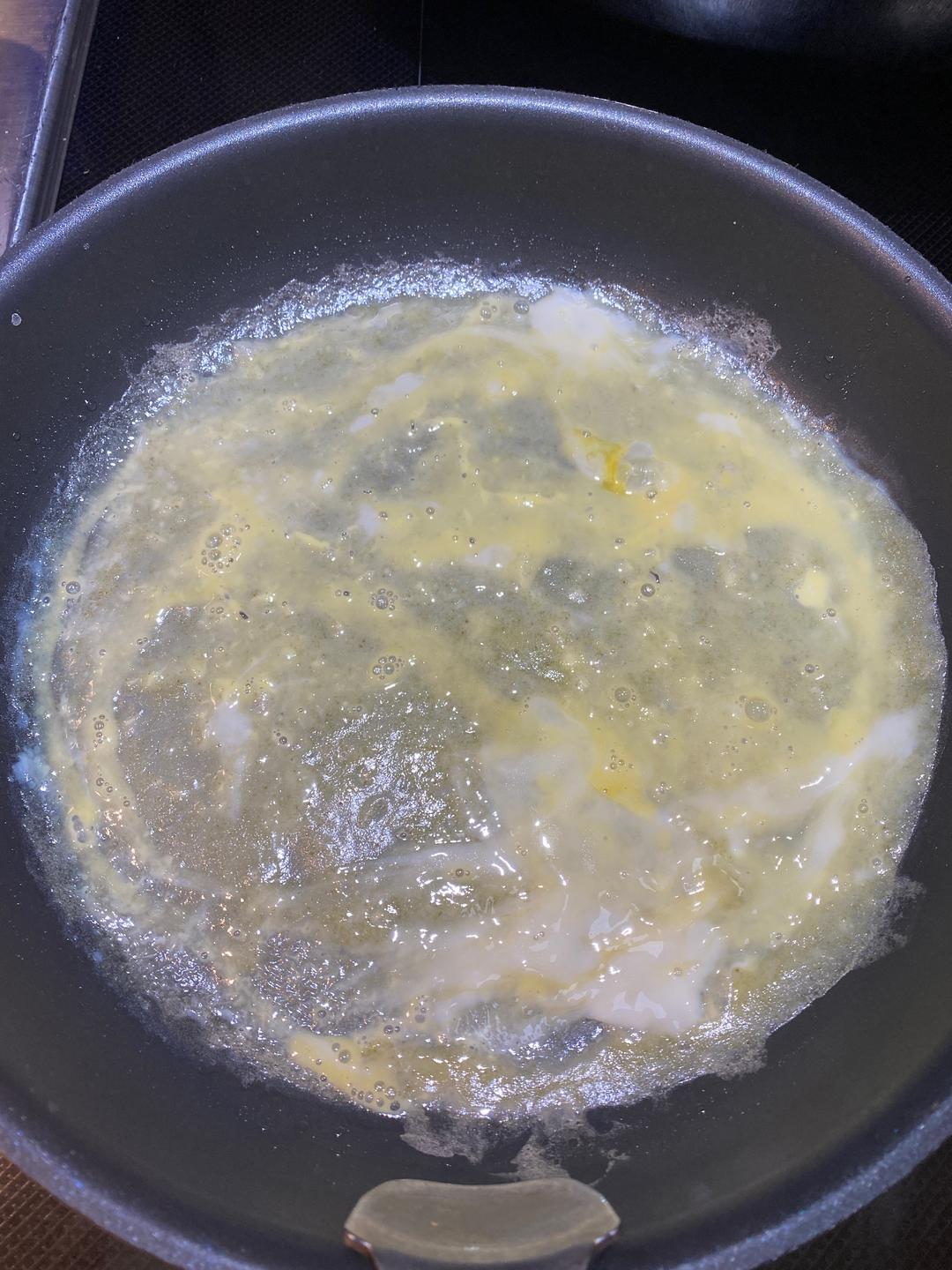 Once the egg is set, brush or spray a little oil over it. Loosen the edges with a spatula, then flip the whole crepe — egg side down on the pan, batter side up.