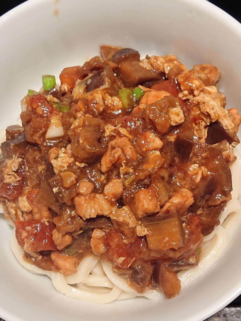 Eggplant noodle sauce in a bowl over hand-pulled noodles with a soft egg