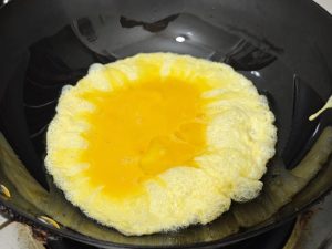 Pour in the beaten egg and let it set