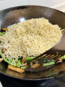 Pour water along the wok edge, keeping the water level about 1 cm below the noodles.