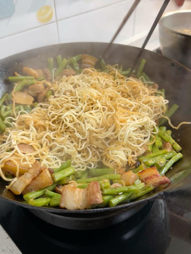 Holding chopsticks in both hands, lift from the bottom of the wok and toss the noodles and vegetables until evenly mixed.