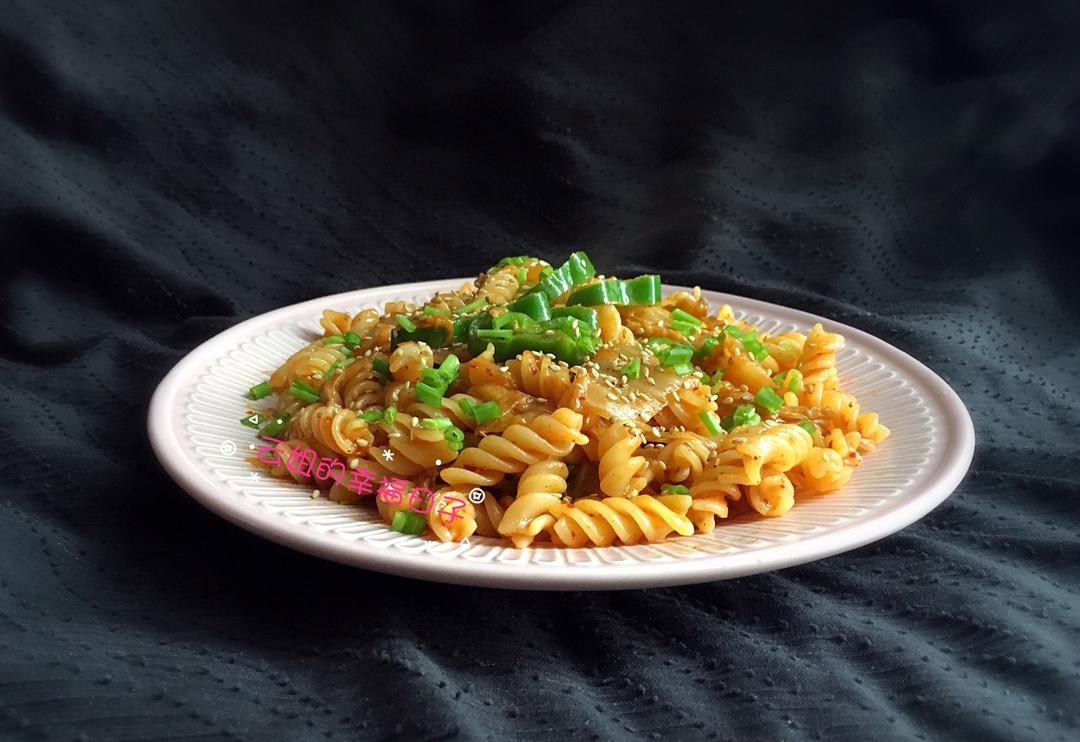 Kimchi fried pasta with red kimchi coating and sesame garnish