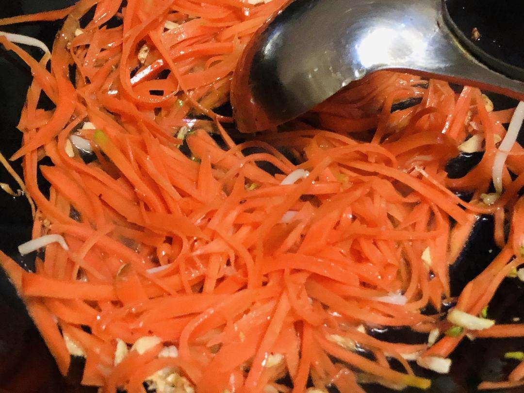 Sizzle the minced garlic in the wok, then add the blanched carrot