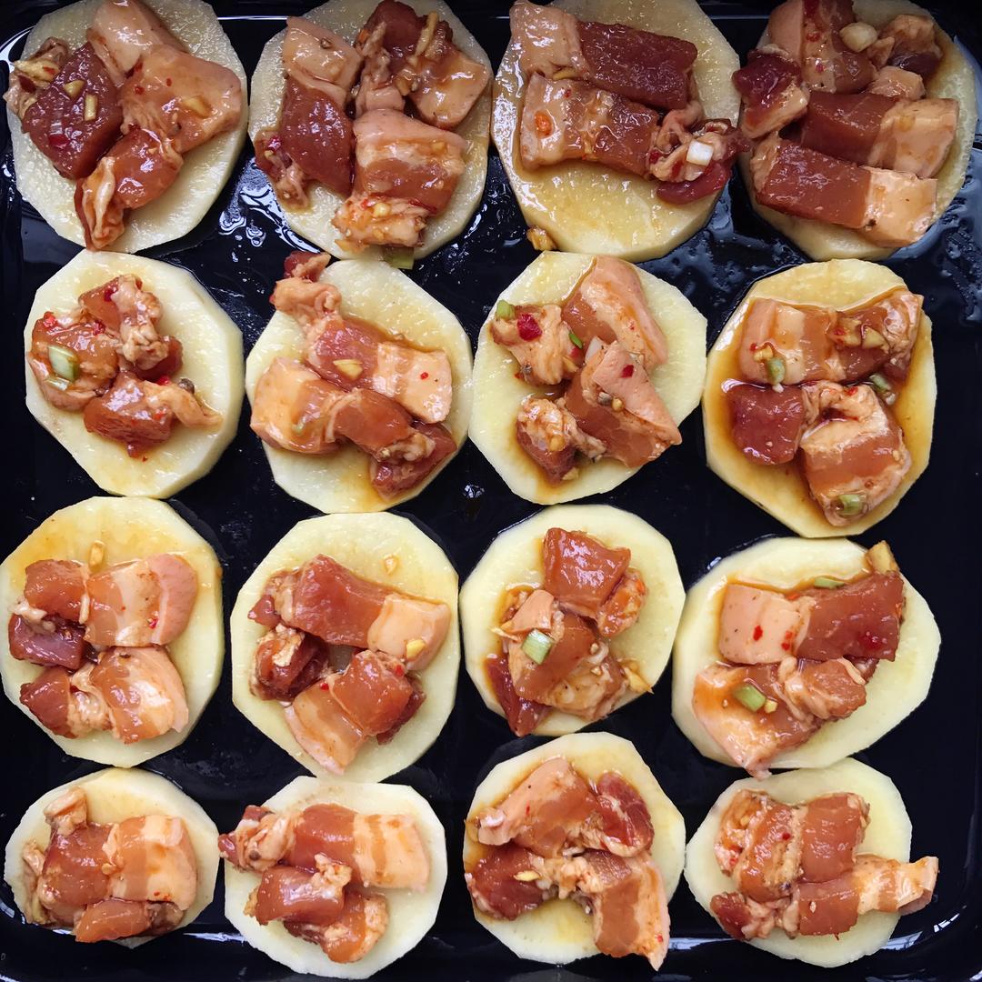 Layer the oiled tray with potatoes, onion, carrot, and pork