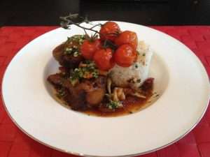 Drizzle the parsley garlic olive oil over the braised oxtail and serve with rice.