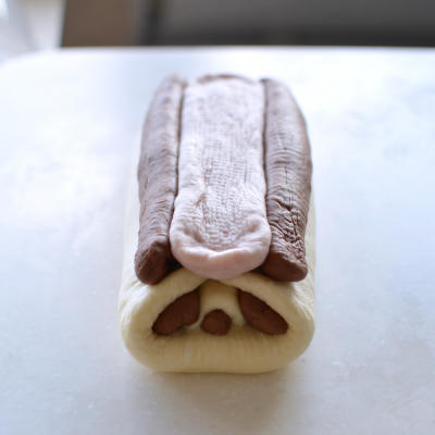 Roll the two 30 g brown pieces into long strips for the ears, then press the flattened pink strip between them.