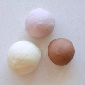 Three colored doughs - white, pink and brown - covered for the first fermentation.