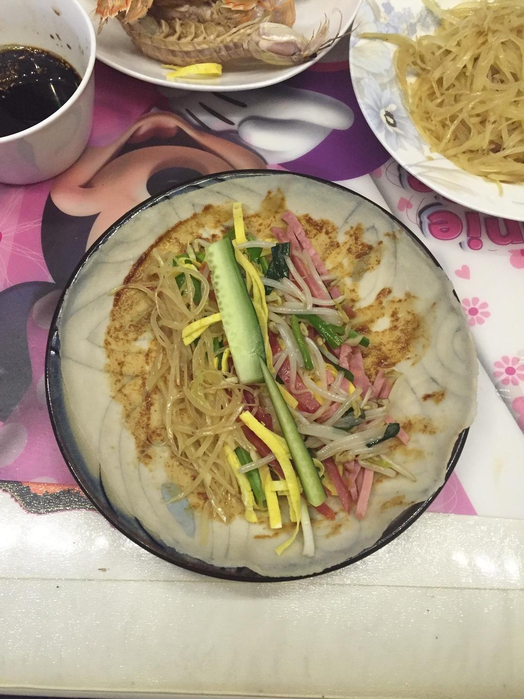 Arrange sweet bean sauce, potato shreds, bean sprouts, ham, egg, scallion, and cucumber