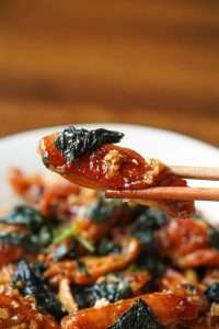 Toss the perilla leaves into the glazed wings for ten seconds until wilted
