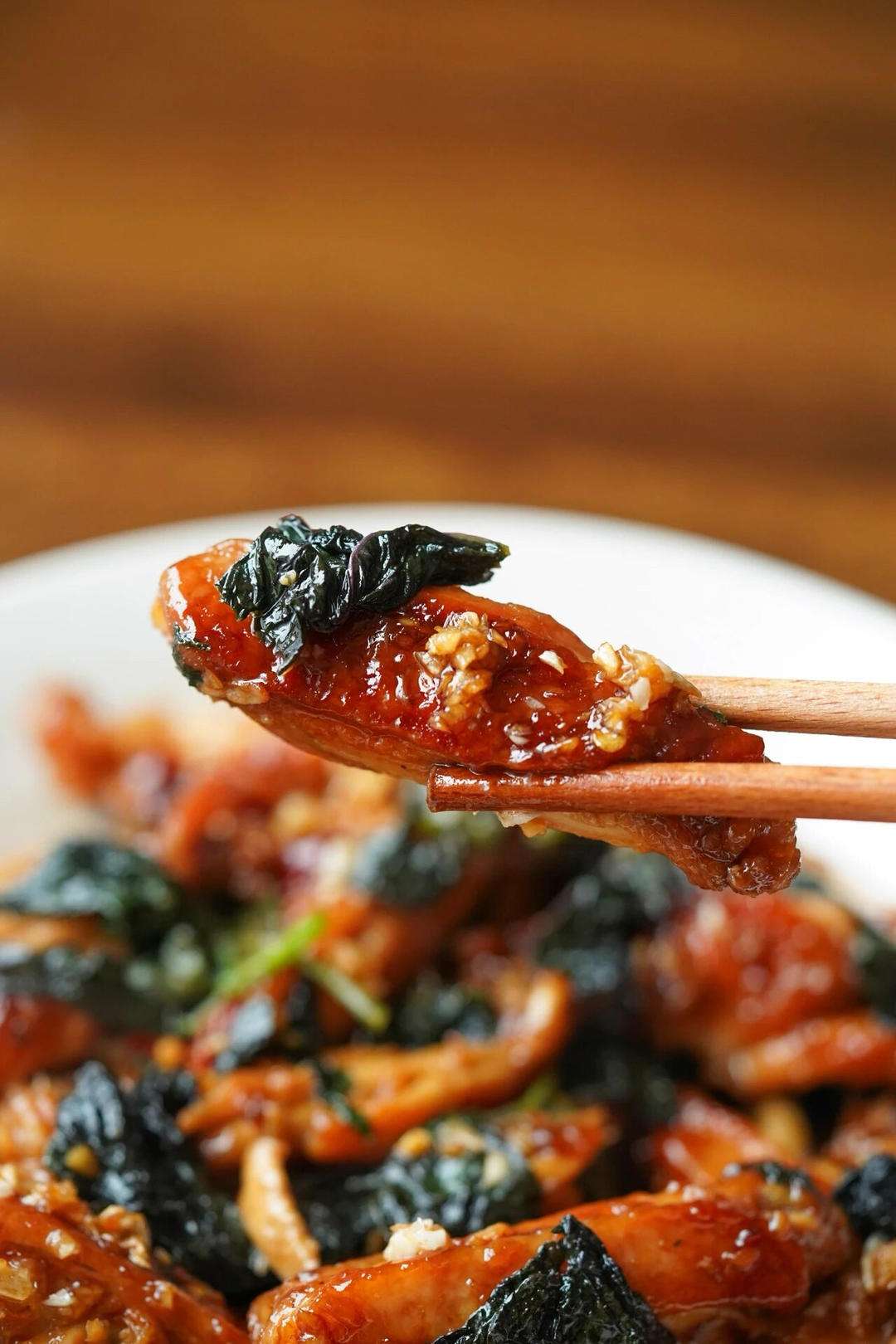 Toss the perilla leaves into the glazed wings for ten seconds until wilted