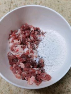 Slice the pork, then chop it a few more times until you have coarse, irregular pieces. Season with the black pepper and salt, add a generous amount of sweet potato starch and a little water.