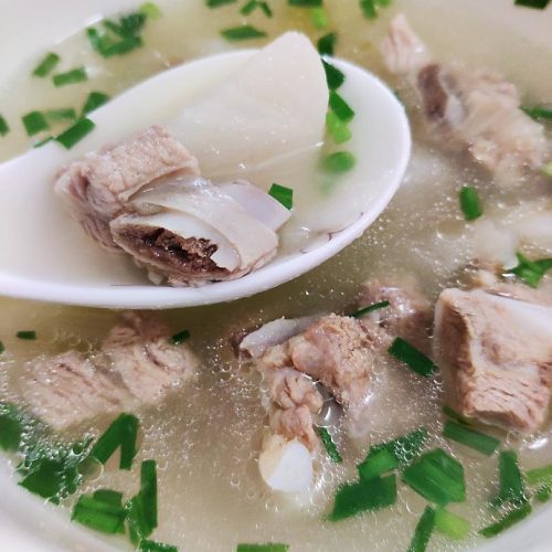 Homemade radish and pork rib soup in a clay pot with clear golden broth, tender daikon chunks and ribs, sprinkled with scallions