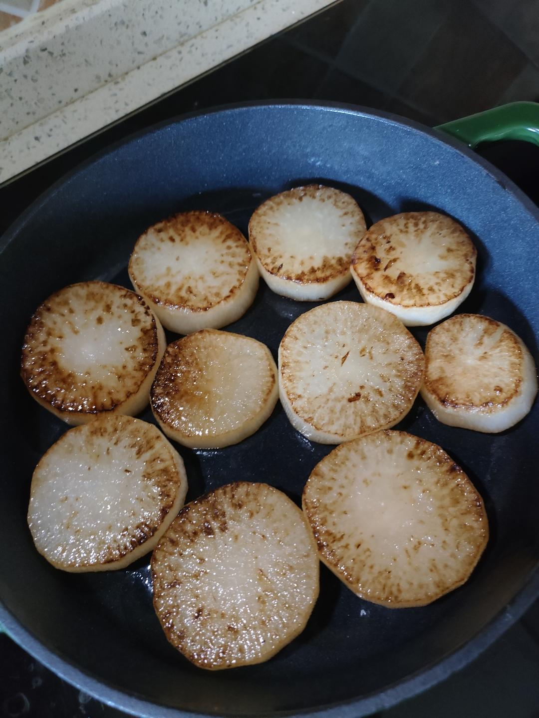 Peel the daikon, cut into thick coins and fry until golden on both sides.