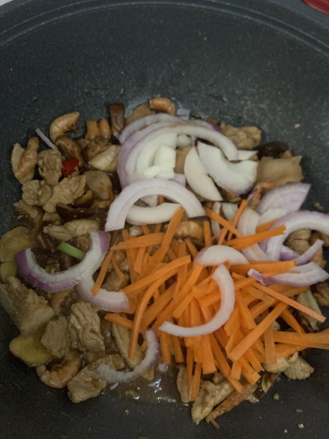 Adding soy sauce, onion and carrot to the wok