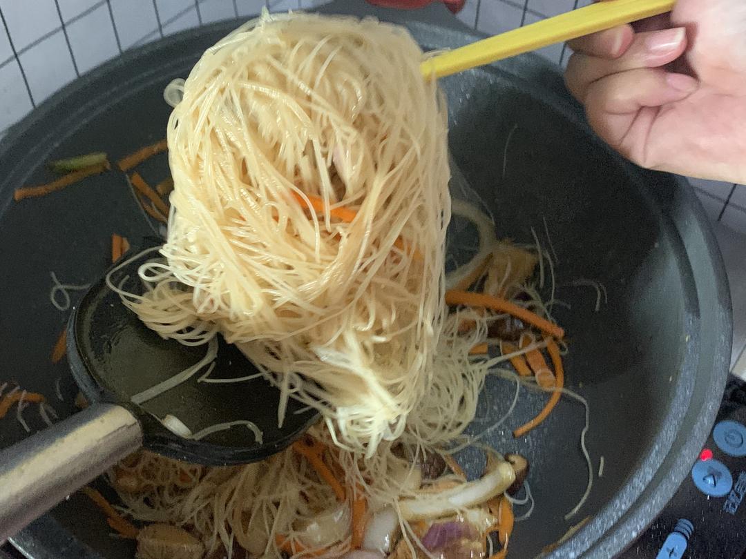 Tossing rice noodles with chopsticks and spatula