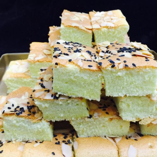Golden sheet pan cake cut into squares with a light, fluffy crumb