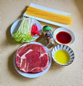 Arrange the steak, pasta, pea shoots, chilies, and seasonings before cooking
