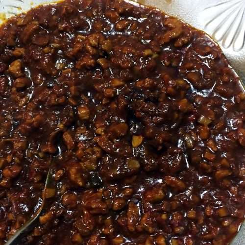 A jar of homemade spicy pork sauce with chunky pork, five-spice tofu, and chili
