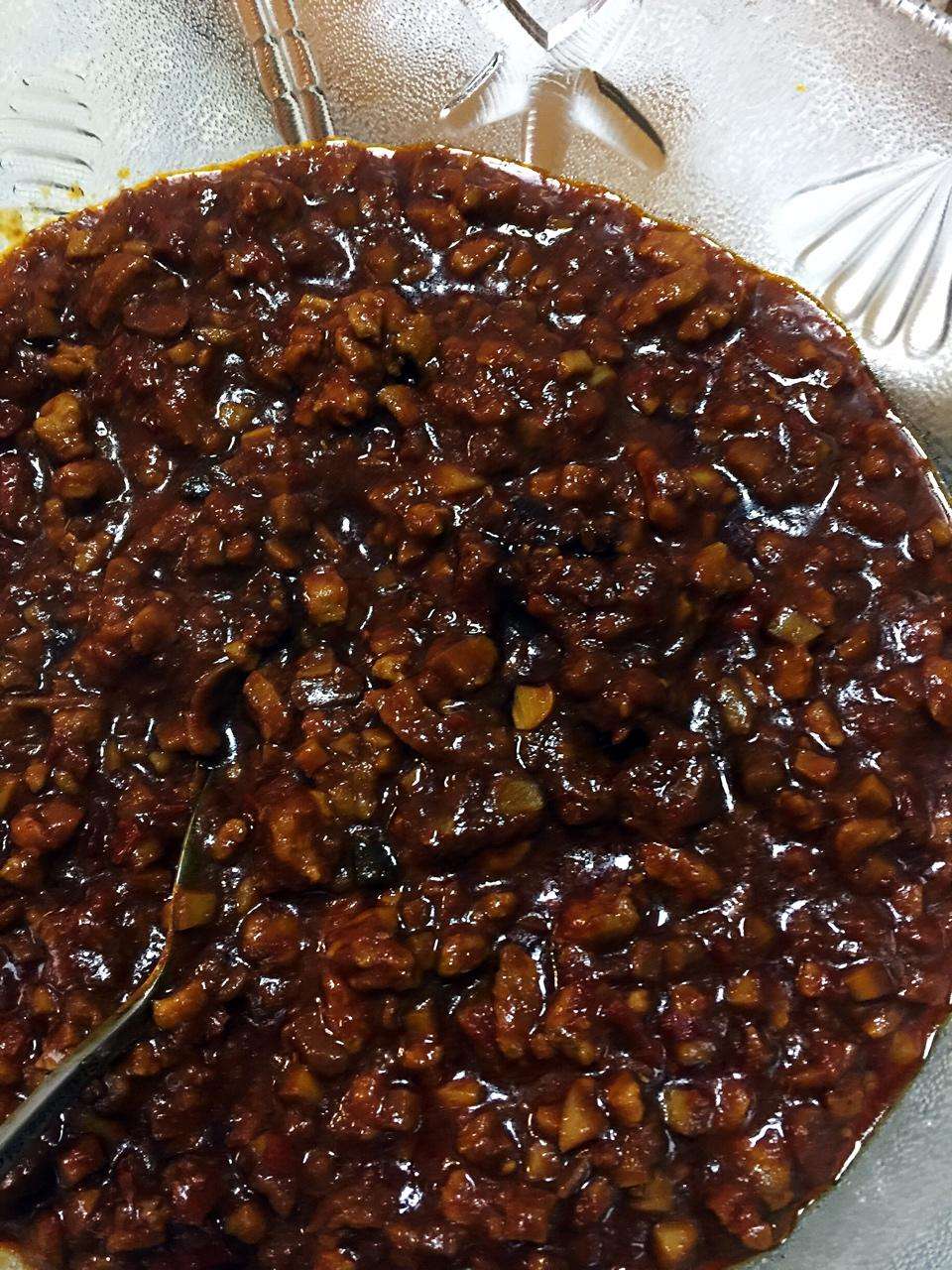 A jar of homemade spicy pork sauce with chunky pork, five-spice tofu, and chili