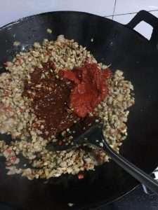 Stir the doubanjiang and chili paste into the pork and tofu until brick red