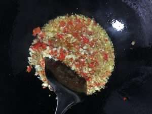 Fry the minced bird's eye chilies, ginger, and garlic in hot oil until fragrant