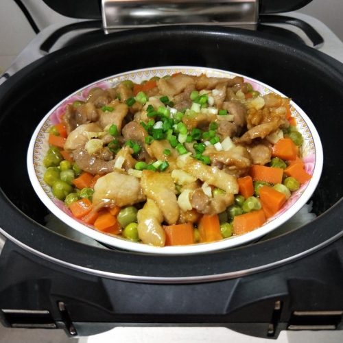 Steamed pork slices over peas and carrots, finished with scallion