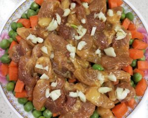 Layer the pork over the vegetables and crush garlic on top
