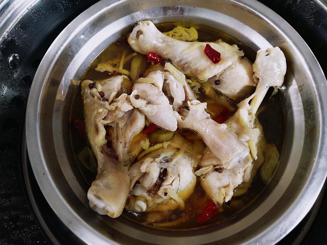 Seasoning marinated chicken drumsticks with soy sauce, peppercorn oil, and dried chilies