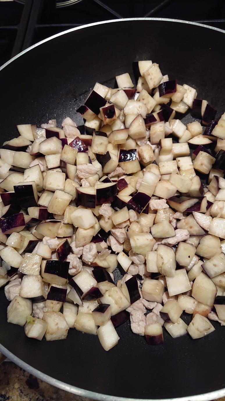 Adding diced eggplant to the wok