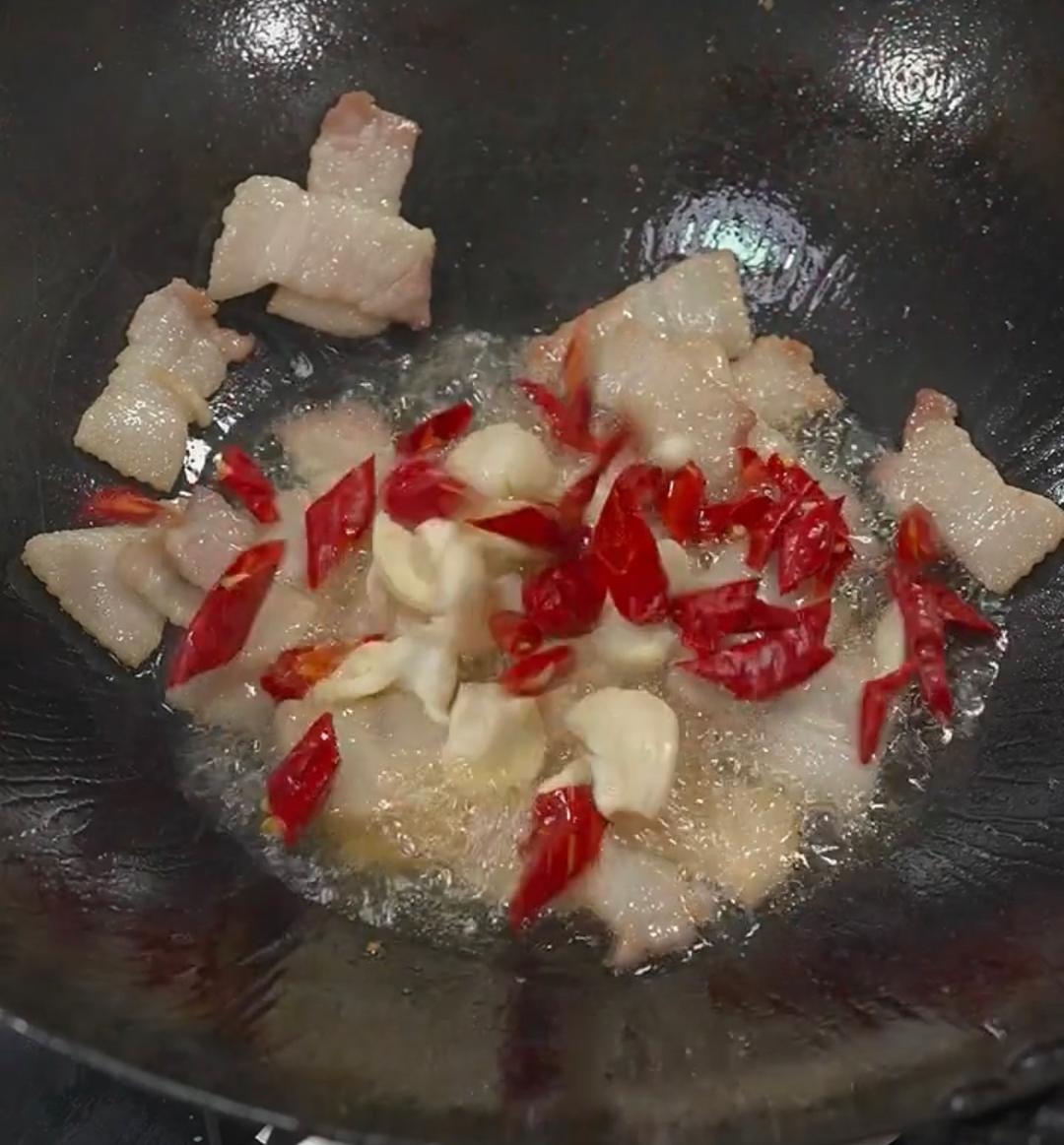 Stir-frying dried chilies and garlic in rendered pork fat