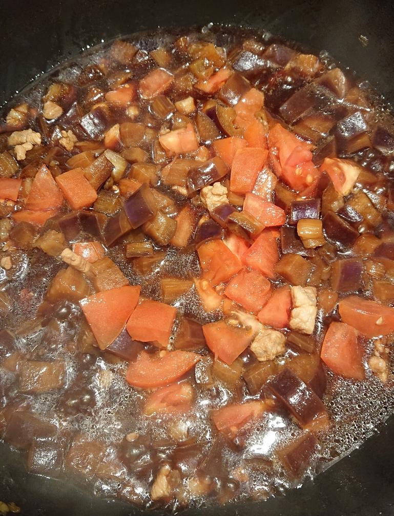 Adding diced tomatoes to the simmering gravy
