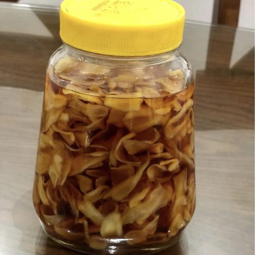 Jar of sweet and sour pickled ginger slices in a clear vinegar brine