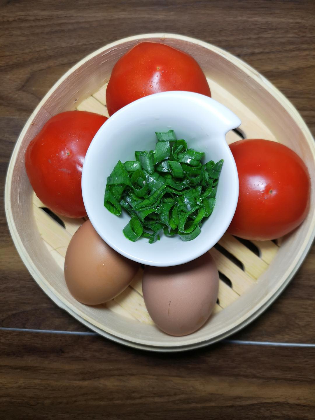 Set up your mise en place: slice the ginger, separate the scallion whites and greens, beat the eggs with a spoonful of cooking wine, and measure the salt. Score the tomatoes with a cross on the bottom of each one and have a pot of boiling water ready on the stove.