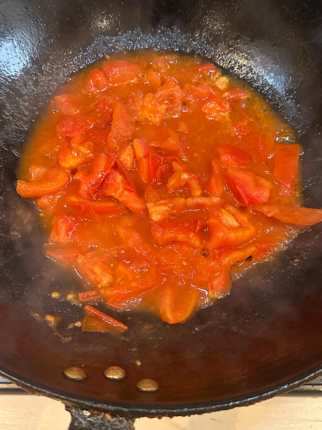 Stir-fry the tomatoes over high heat with salt and sugar until they soften and release a glossy red sauce.