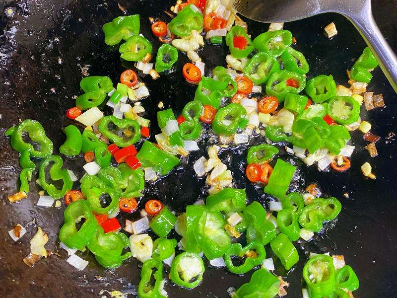 Chopped chilies dry-frying in the wok, skins blistering and charring at the edges