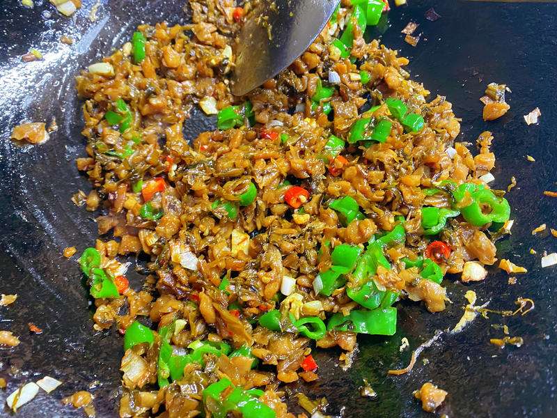Waipocai pickled greens added to the wok with the blistered chilies, eggs returning for the final toss