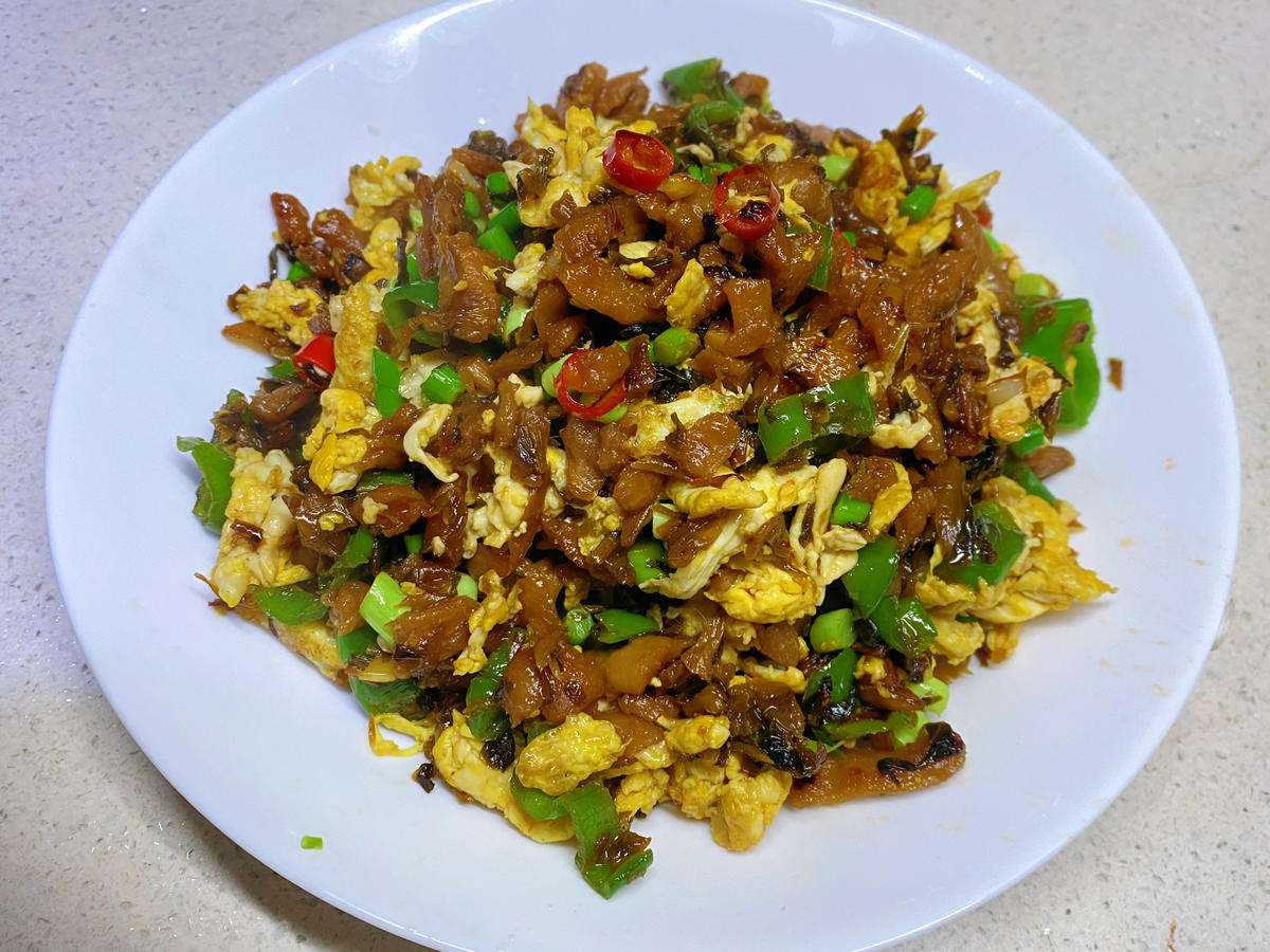 Waipocai chao dan - grandma's pickled greens stir-fried with soft eggs, chilies, and garlic scapes in a wok
