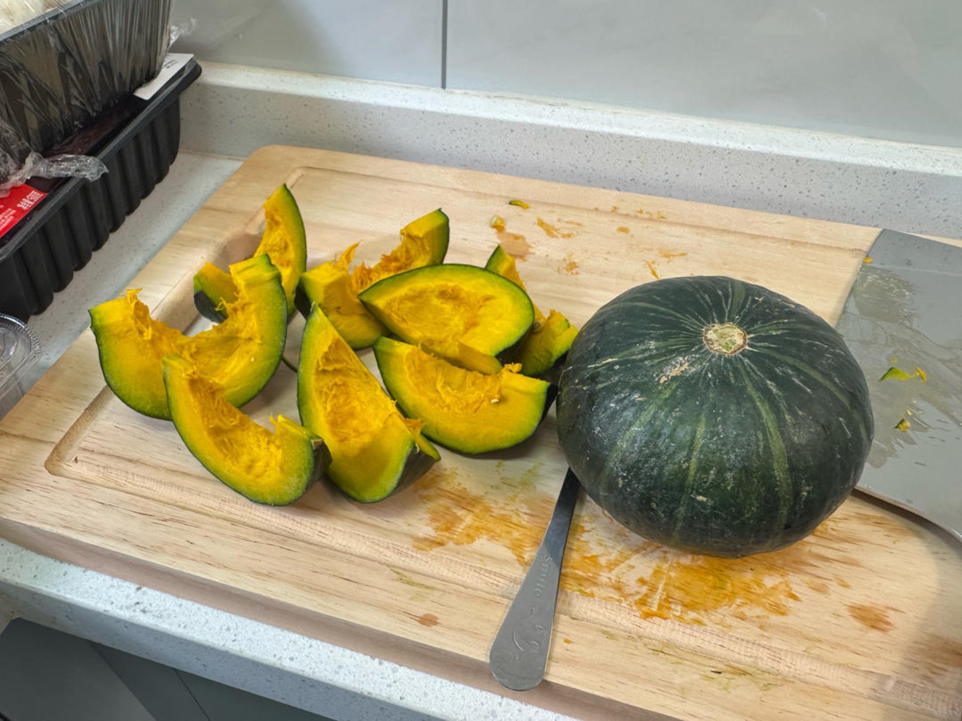 Kabocha pumpkin wedges with seeds scooped out on a cutting board