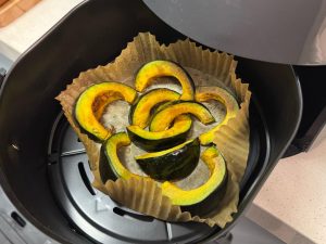 Kabocha pumpkin wedges roasting in an air fryer basket