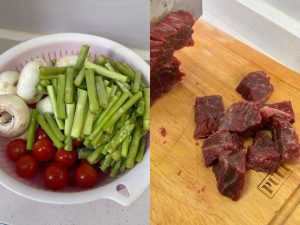 Cubed beef, mushrooms, asparagus, and cherry tomatoes prepped on a board