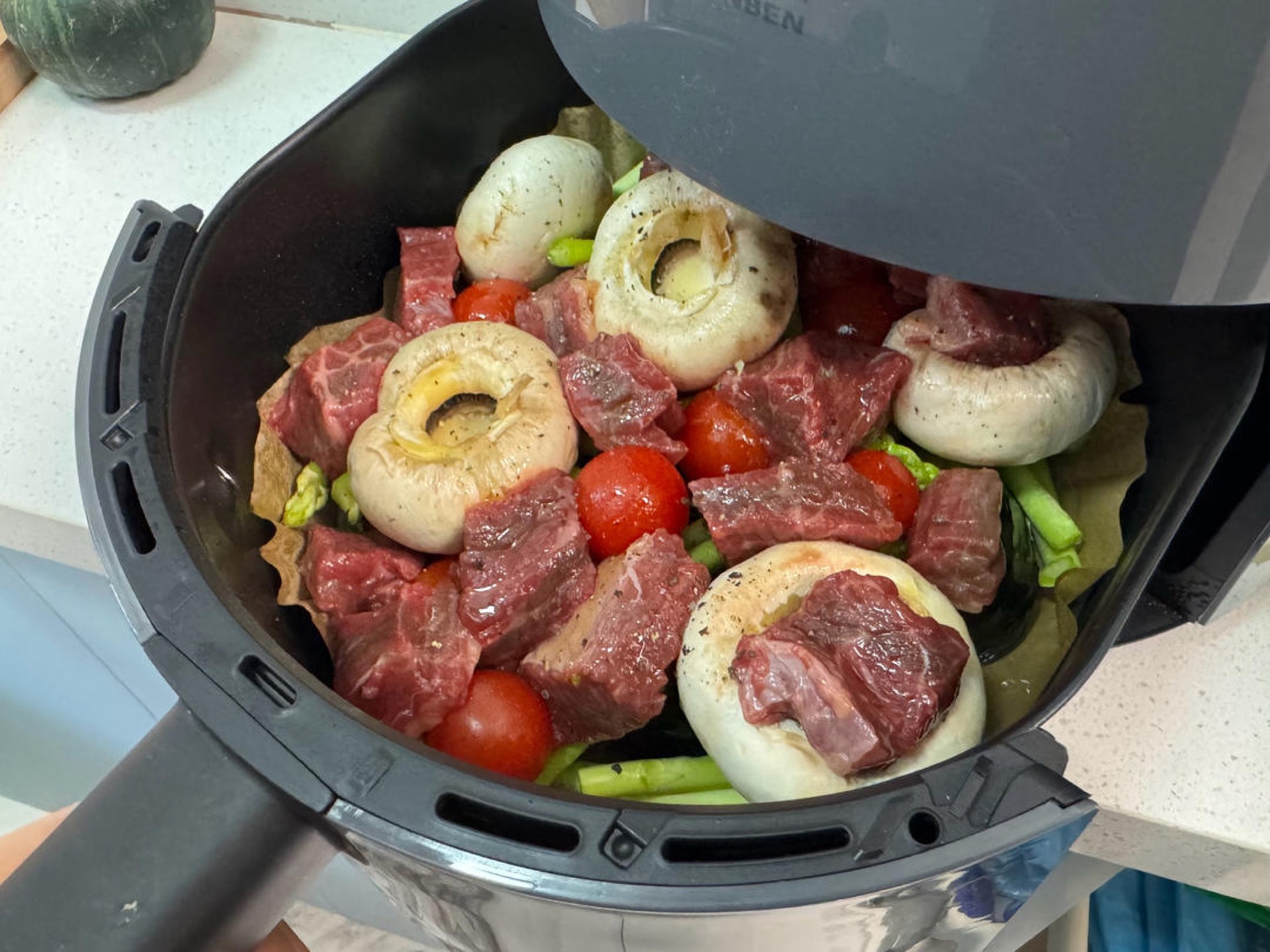 Beef and vegetables cooking together in the air fryer basket