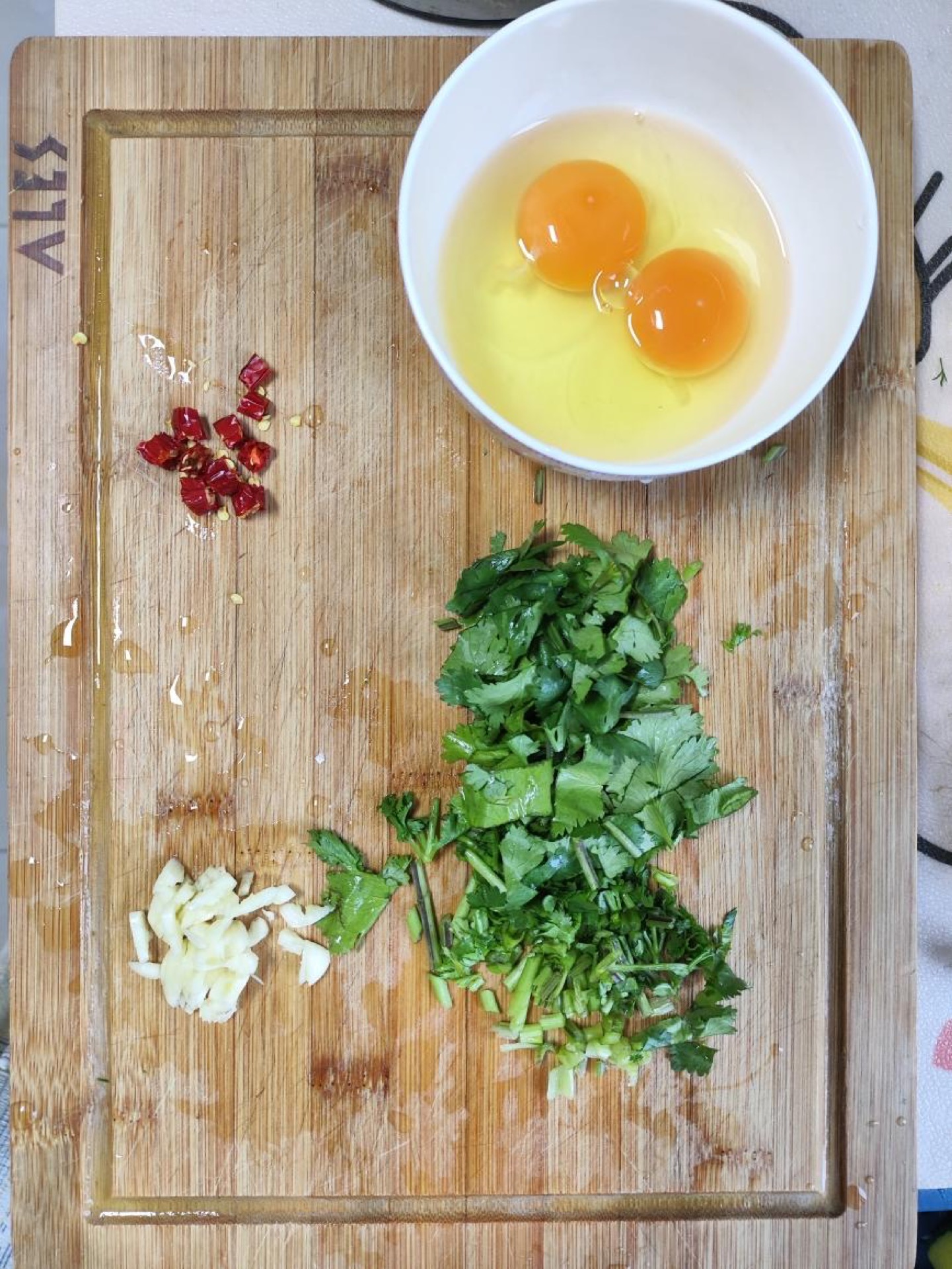 Beat the eggs, slice the red chili into rings, chop the cilantro, and mince the garlic.