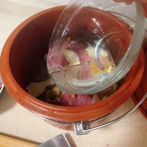 Meatballs and herbs in a ceramic double boiler pot before water is added