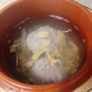 Boiling water being poured over the meatballs and herbs in the soup pot