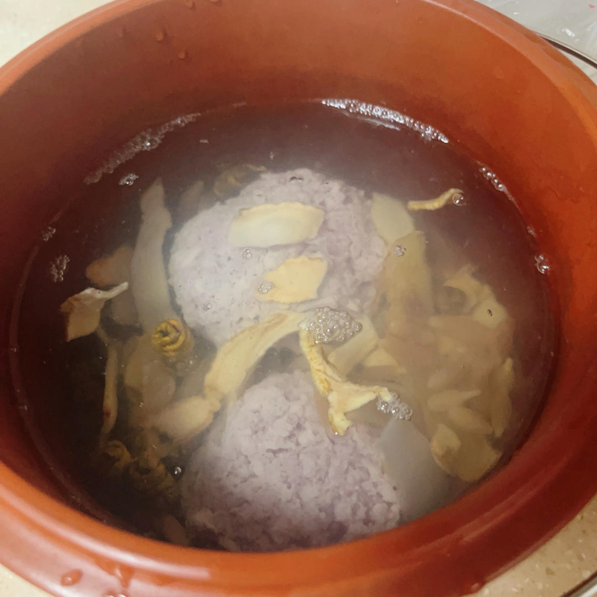 Boiling water being poured over the meatballs and herbs in the soup pot