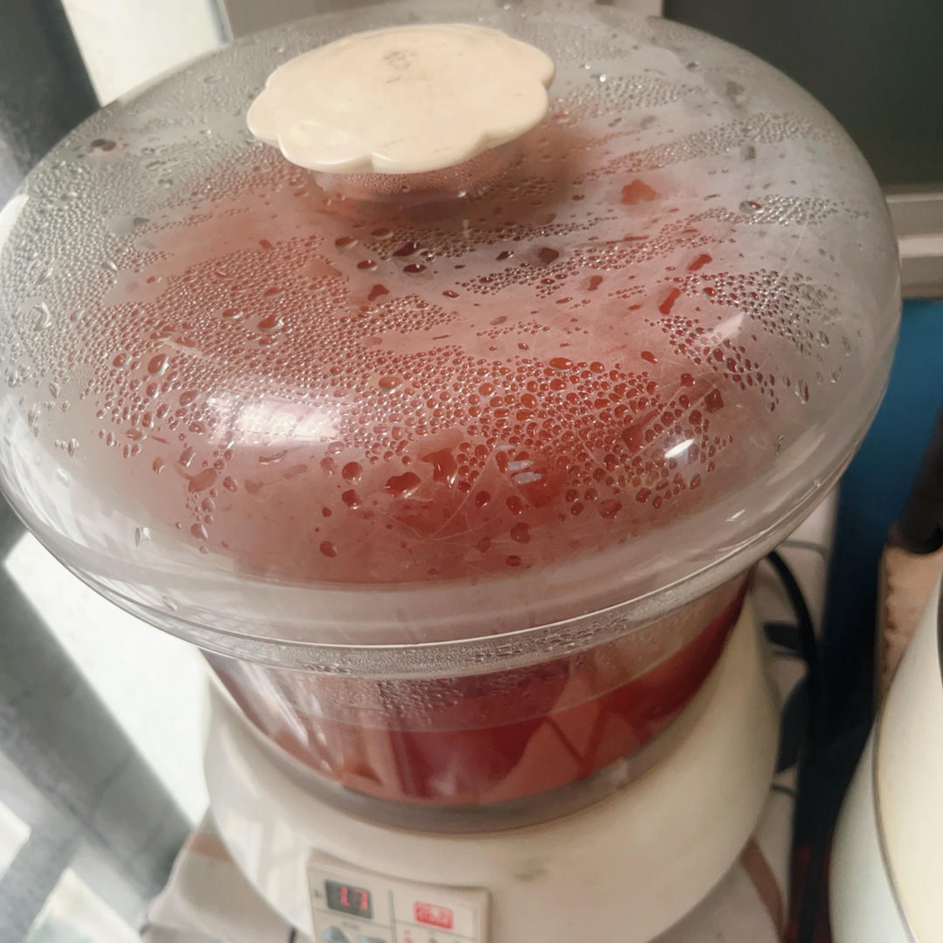 Covered ceramic soup pot double boiling inside a larger pot of simmering water
