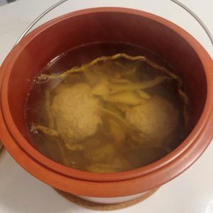 Clear golden American ginseng dendrobium lean pork soup served in a small white bowl